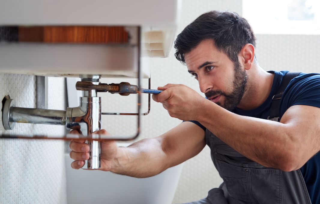 Plumber repairing the drain pipe under a bathroom sink