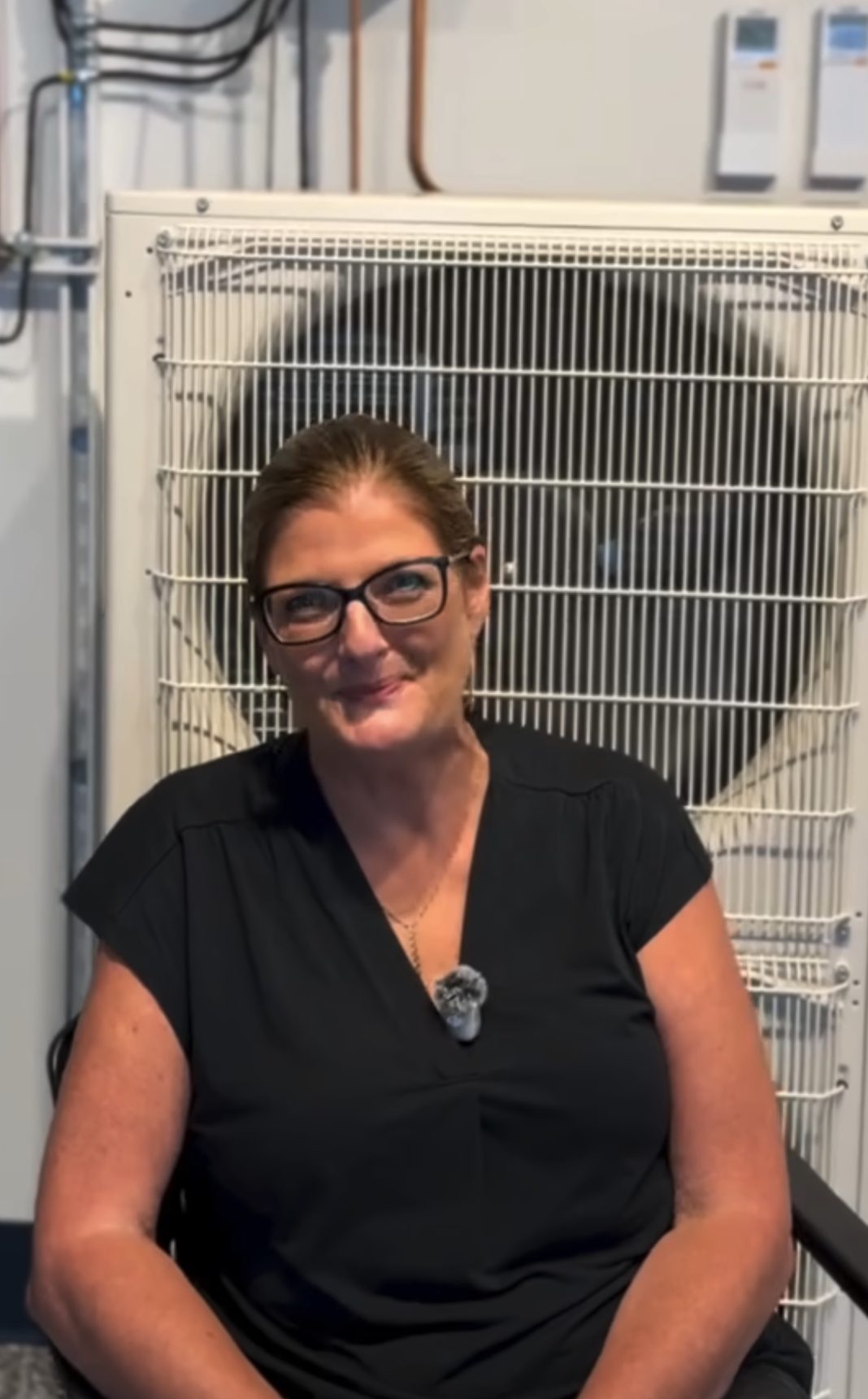 Smiling homeowner sitting in front of her new heat pump