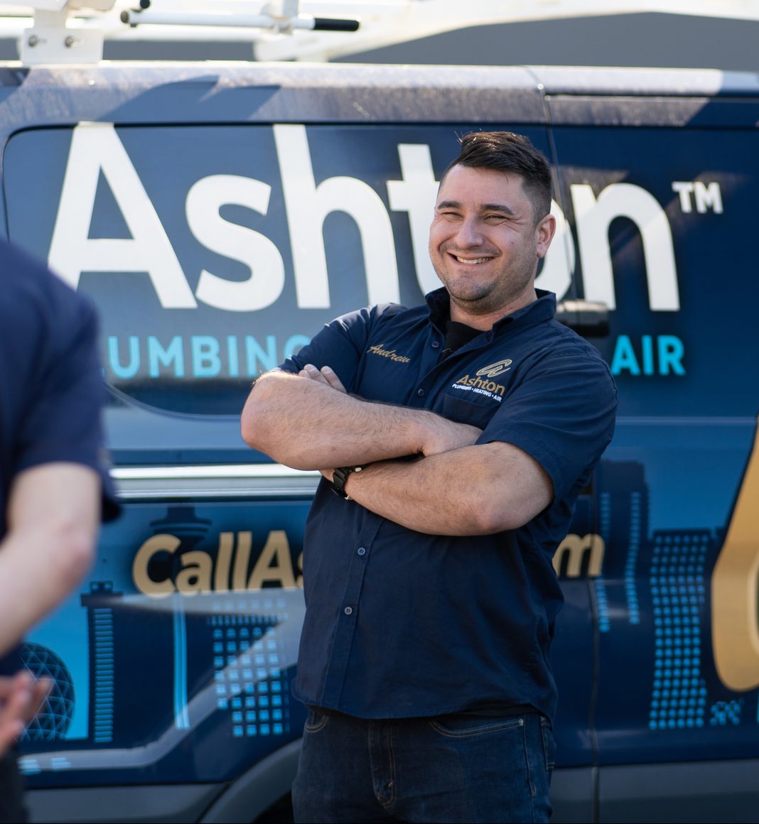 Ashton technician standing with arms crossed in front of an Ashton service van