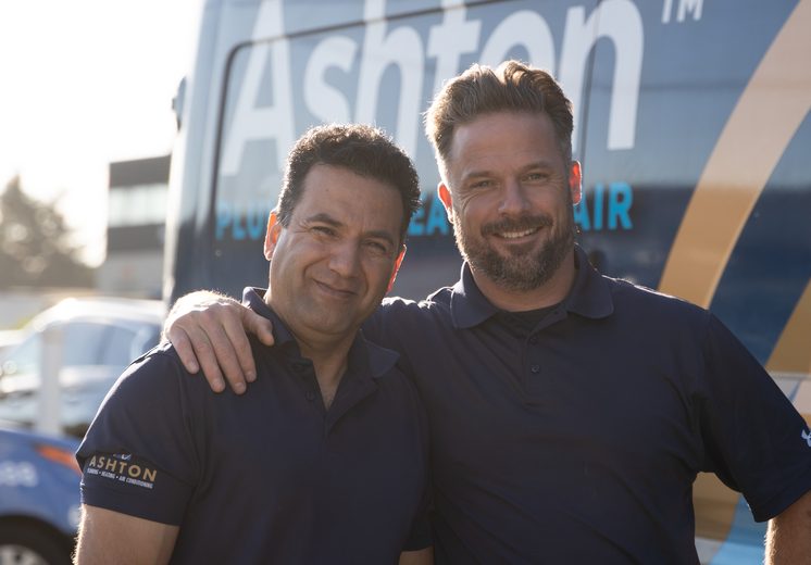 Two smiling Ashton technicians in front of an Ashton service van