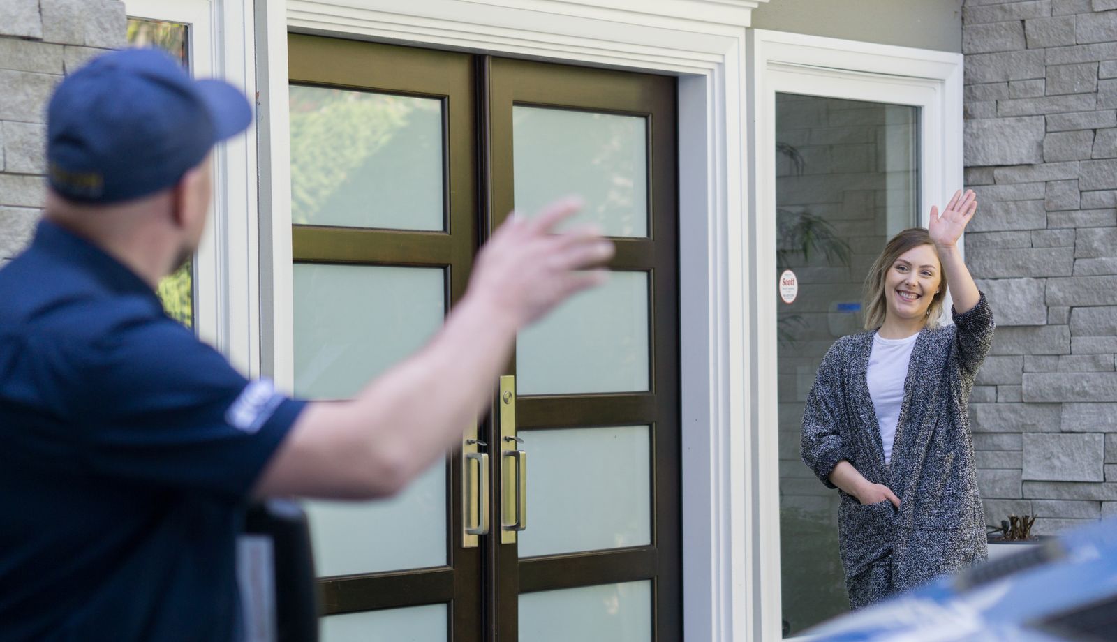 Ashton technician waving to a smiling homeowner at her front door